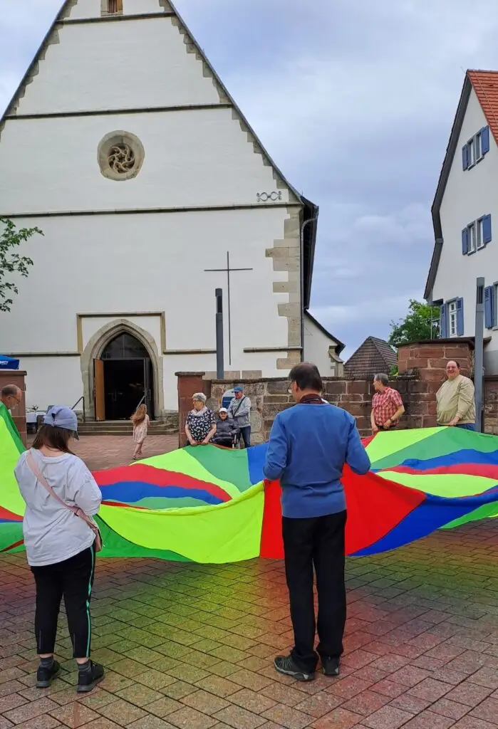 Menschen spielen gemeinsam mit einem bunten Schwungtuch