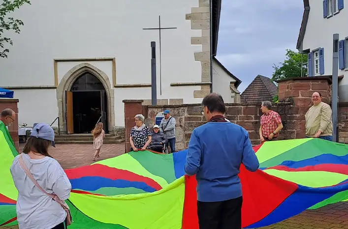 Menschen spielen gemeinsam mit einem bunten Schwungtuch