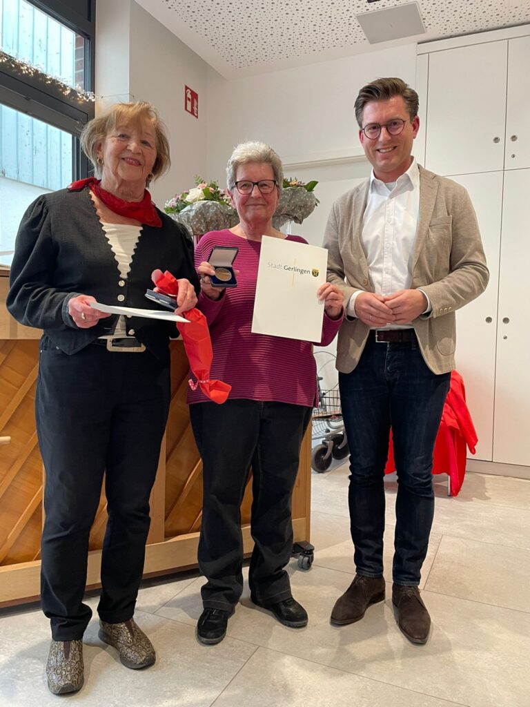 Ehrung im Freizeitclub Gerlingen: Zwei engagierte Frauen präsentieren stolz ihre Urkunde und Medaille neben einem offiziellen Vertreter in einem hellen Festsaal.