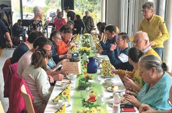 Gruppe sitzt zusammen am Tisch beim gemeinsamen Kuchenessen